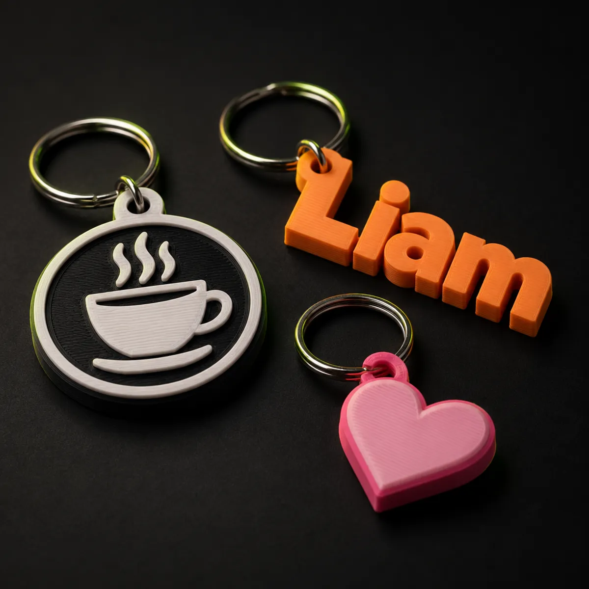 Três chaveiros impressos em 3D: um logo de café, um nome e um coração